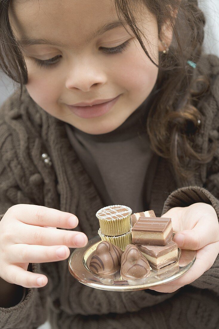 Girl taking a chocolate from a small tray of chocolates