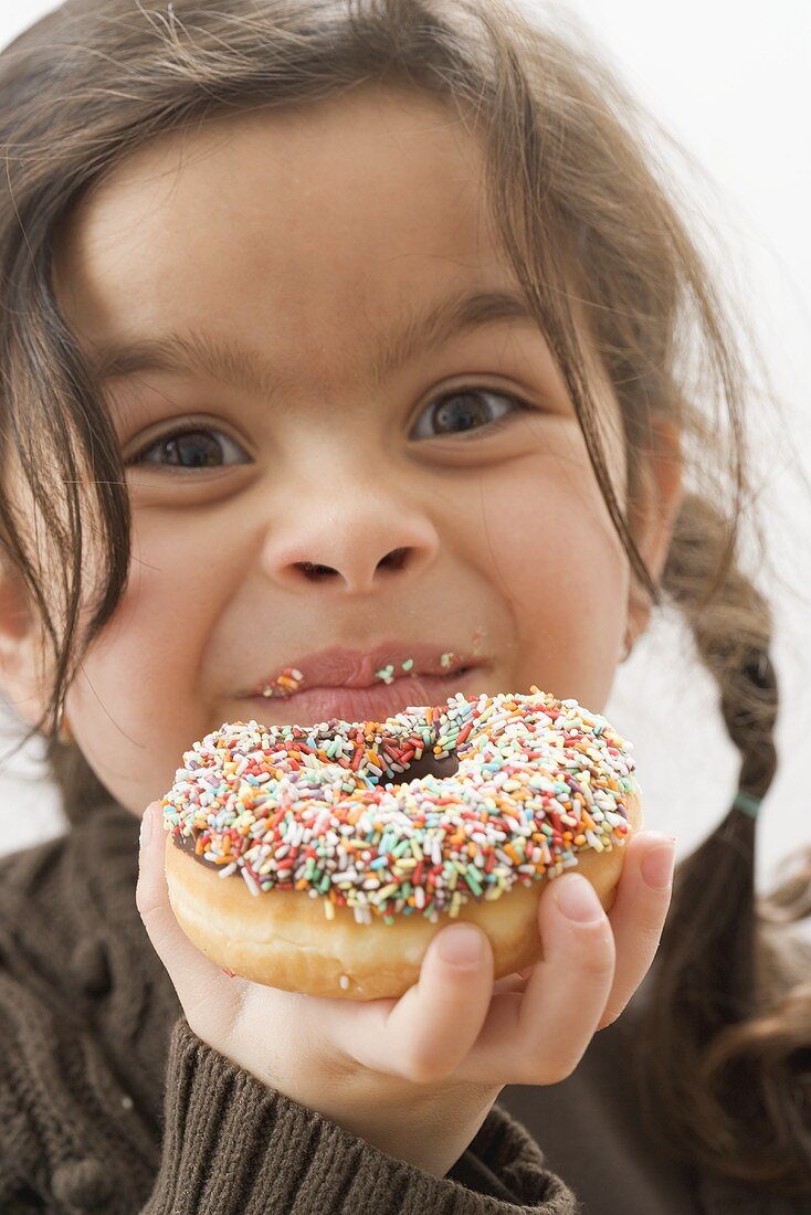 Mädchen mit einem angebissenen, bunten Donut