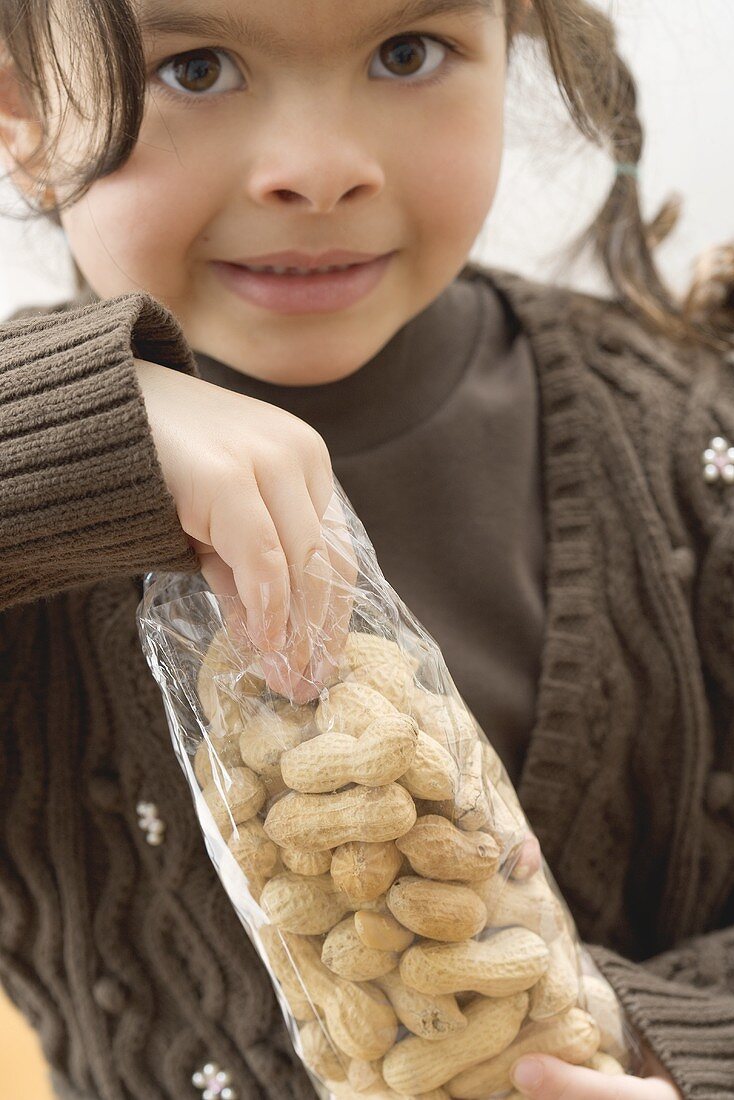 Mädchen greift in eine Tüte mit Erdnüssen