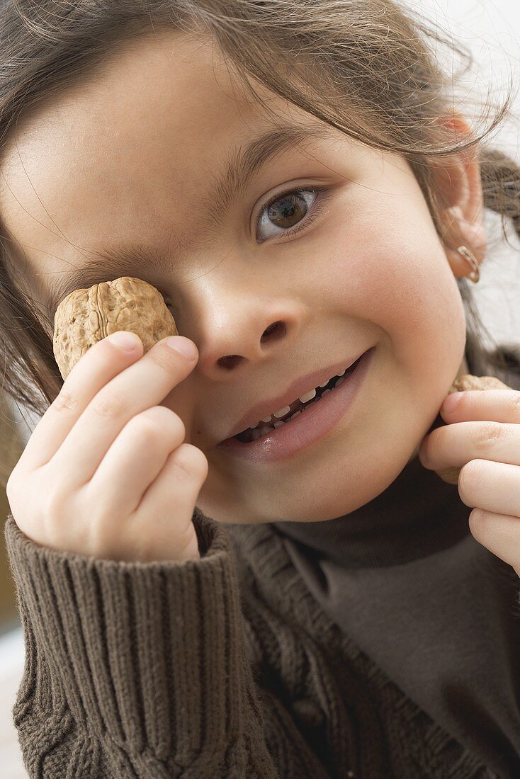 Girl holding a walnut in front of her eye