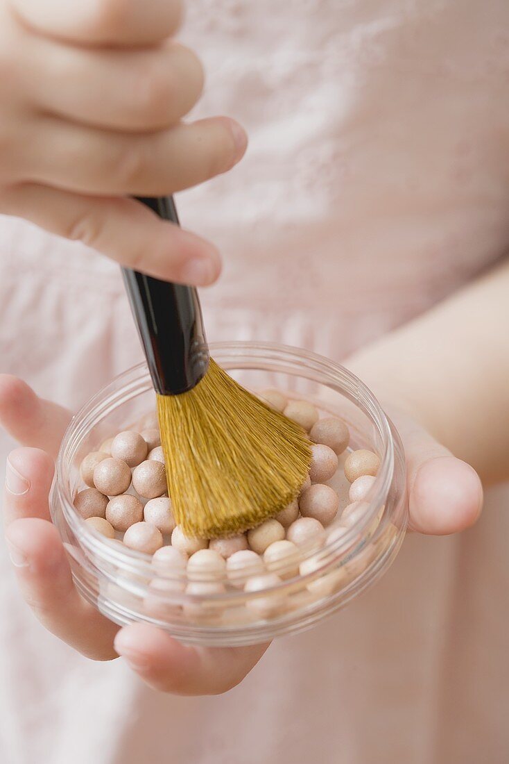 Girl holding powder pearls and brush