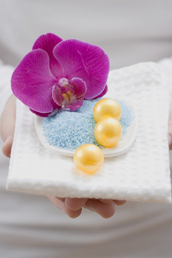 Young woman holding bath salts and bath pearls with orchid