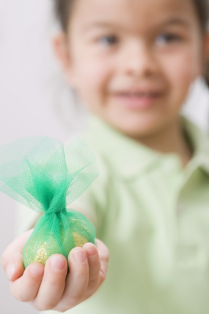 Mädchen mit einem goldenen Ei in einem grünen Netz