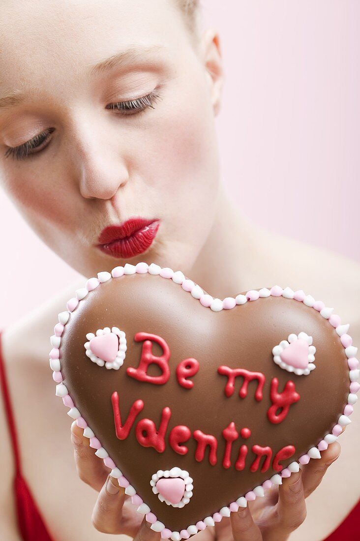Young woman holding a chocolate heart for Valentine's Day