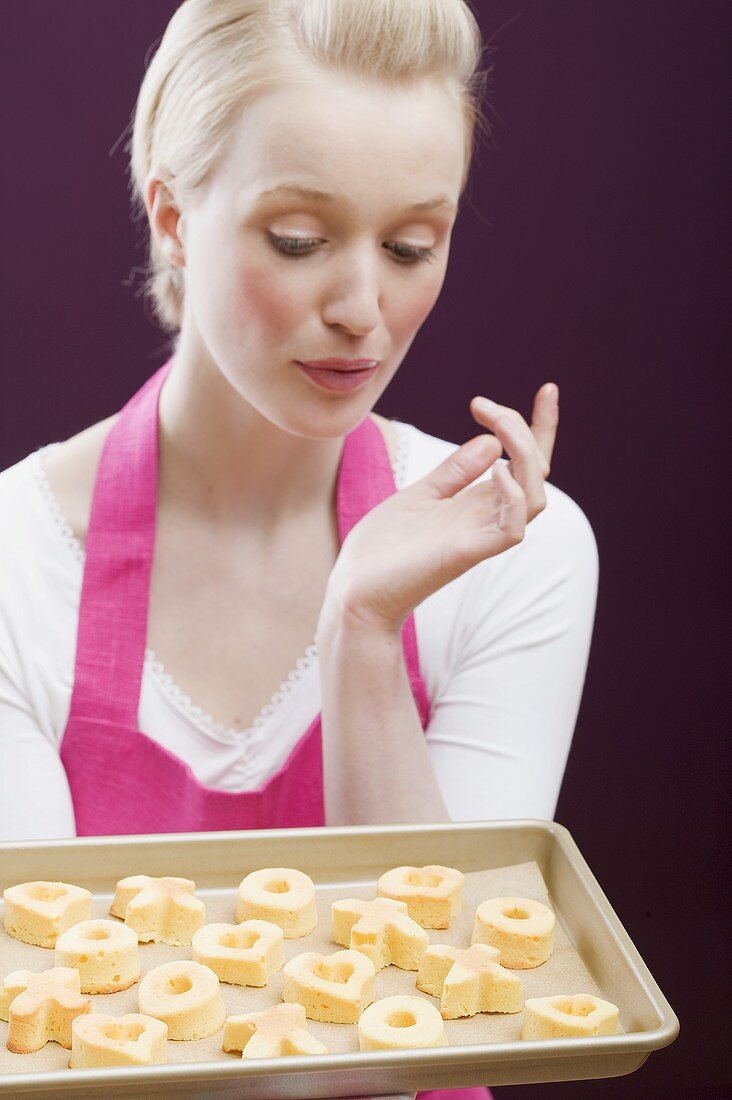 Junge Frau mit einem Backblech frisch gebackenen Keksen