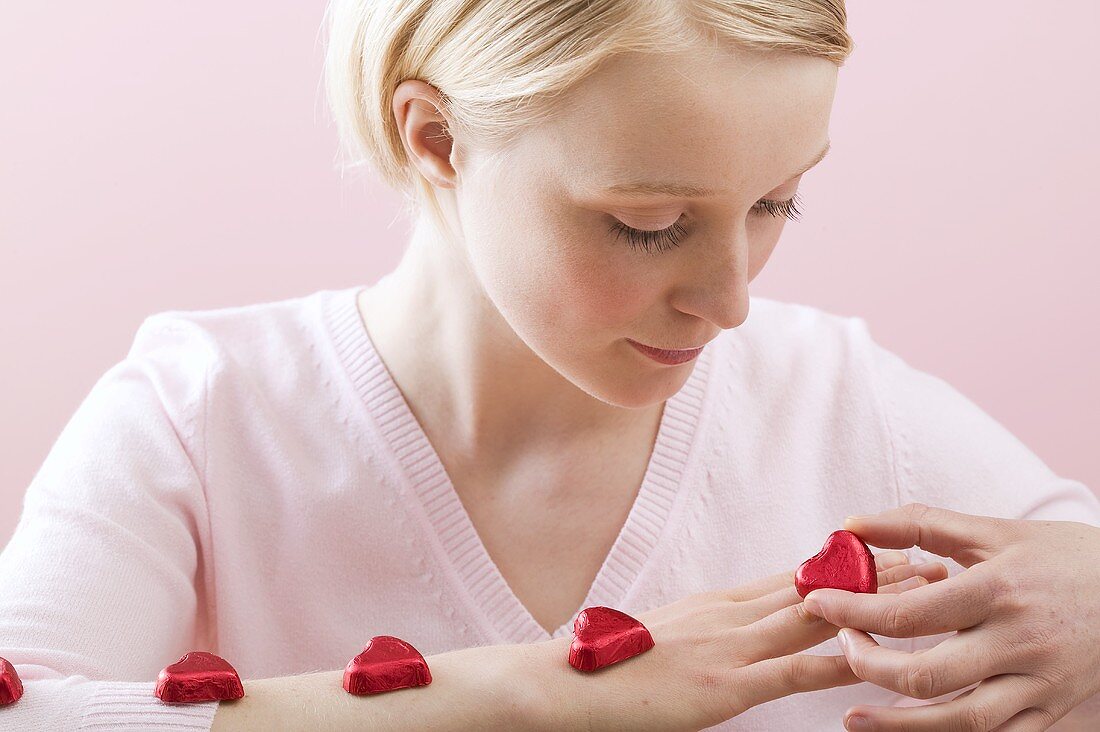 Young woman with red chocolate hearts on her arm