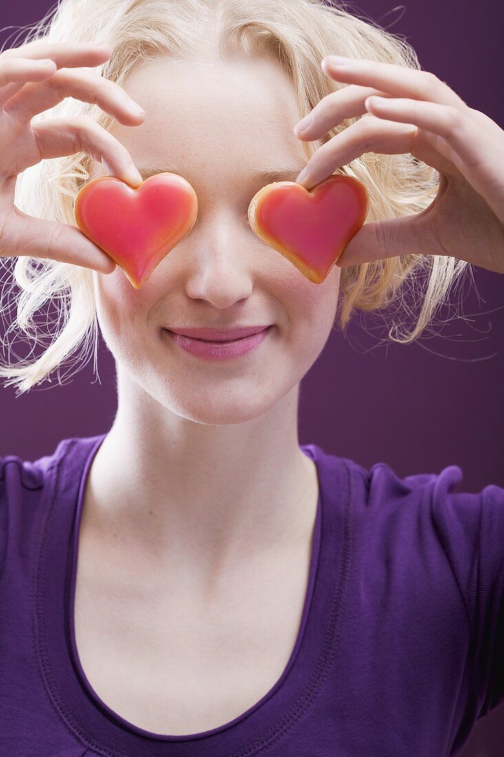 Young woman holding hearts in front of her eyes