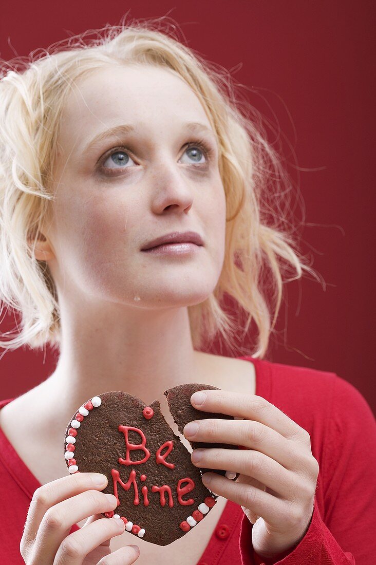 Sad young woman with a broken chocolate heart