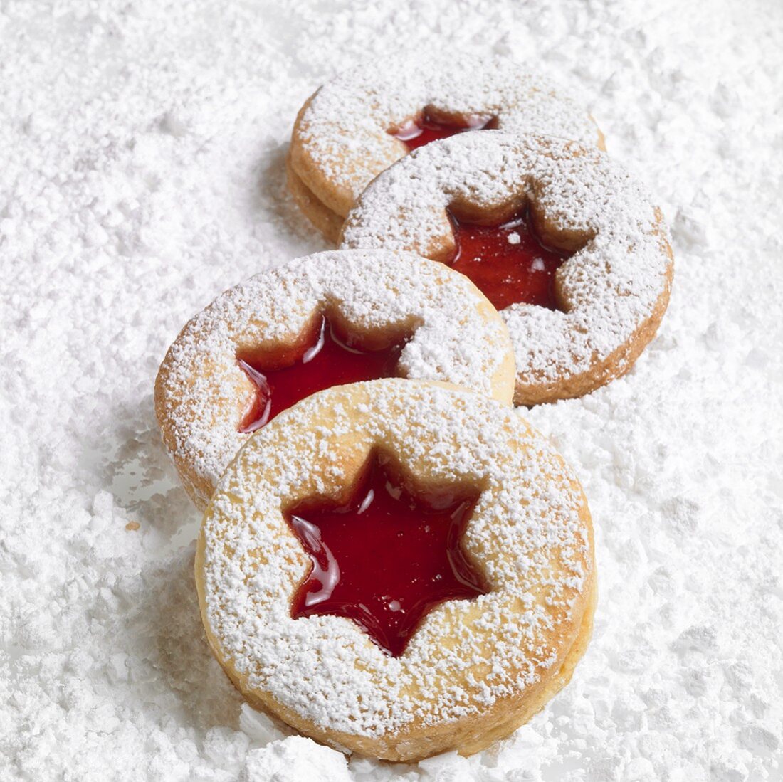 Four Linzer biscuits on icing sugar