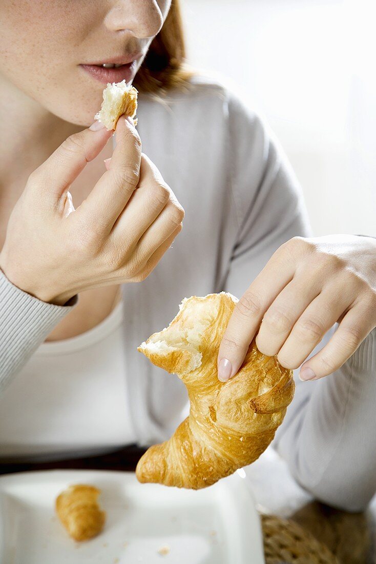 Young woman eating croissant