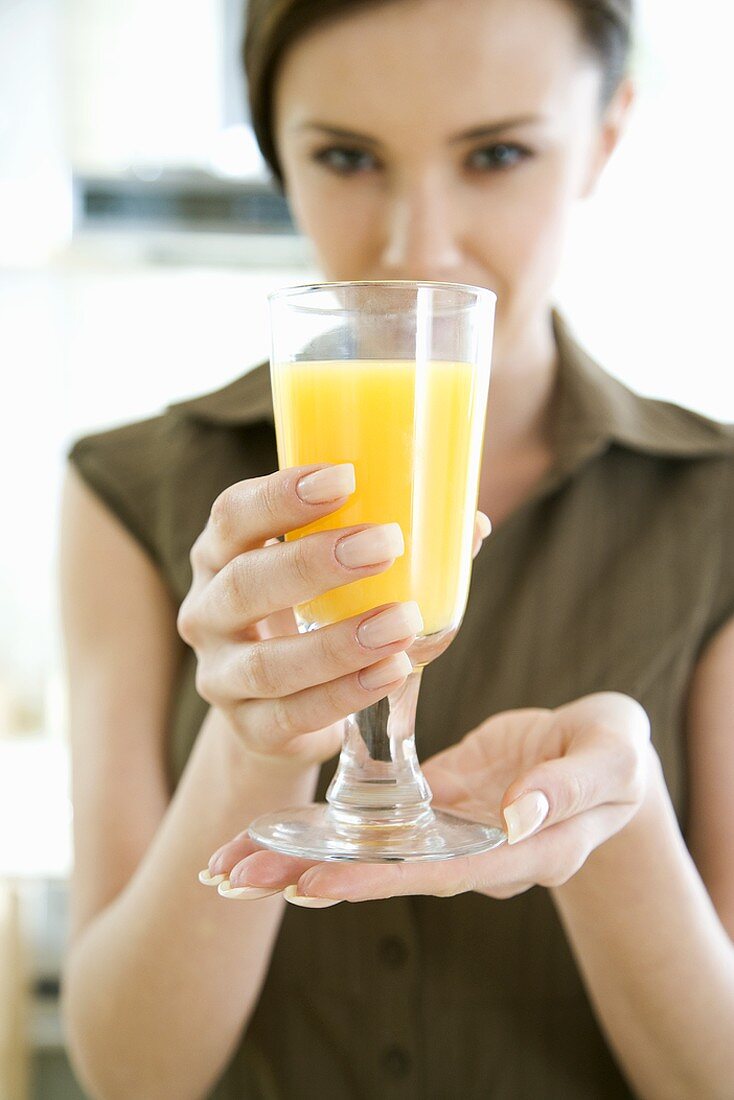 Junge Frau hält ein Glas Orangensaft