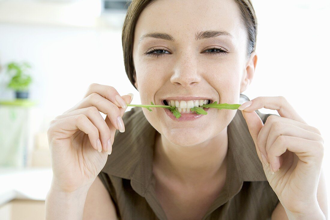 Young woman with a rocket leaf in her mouth