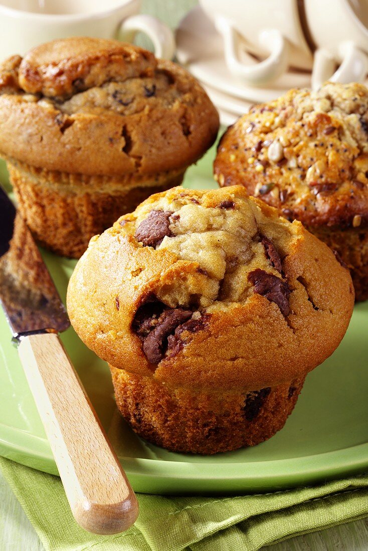 Three different muffins, teacups in background