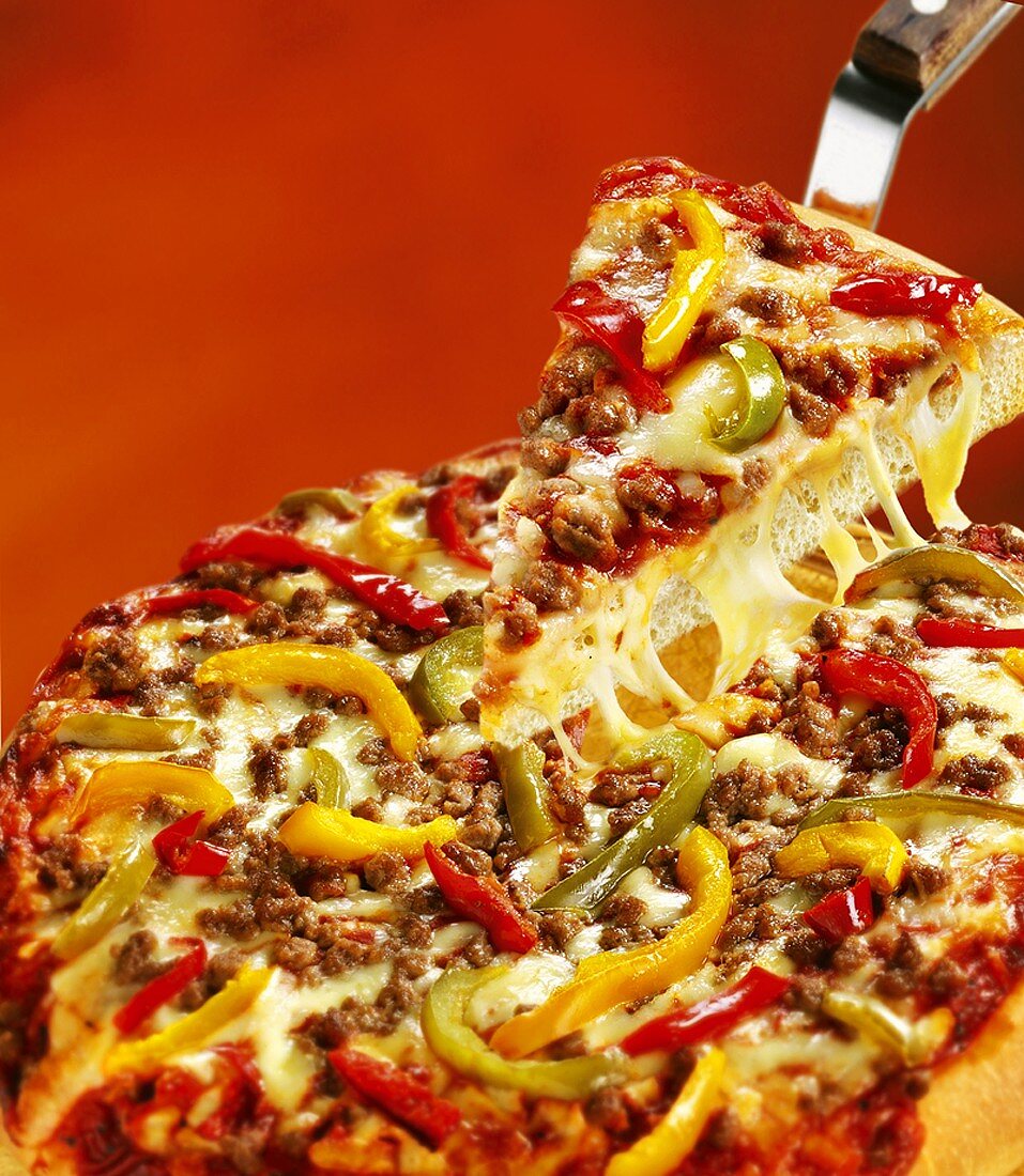 Pizza mit Rinderhack und Paprika, ein Stück auf Pizzaheber