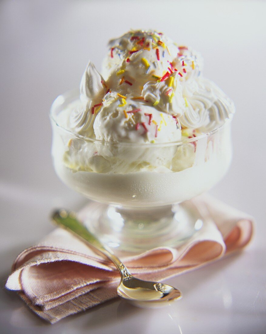 Vanilla ice cream, cream and sprinkles in sundae glass