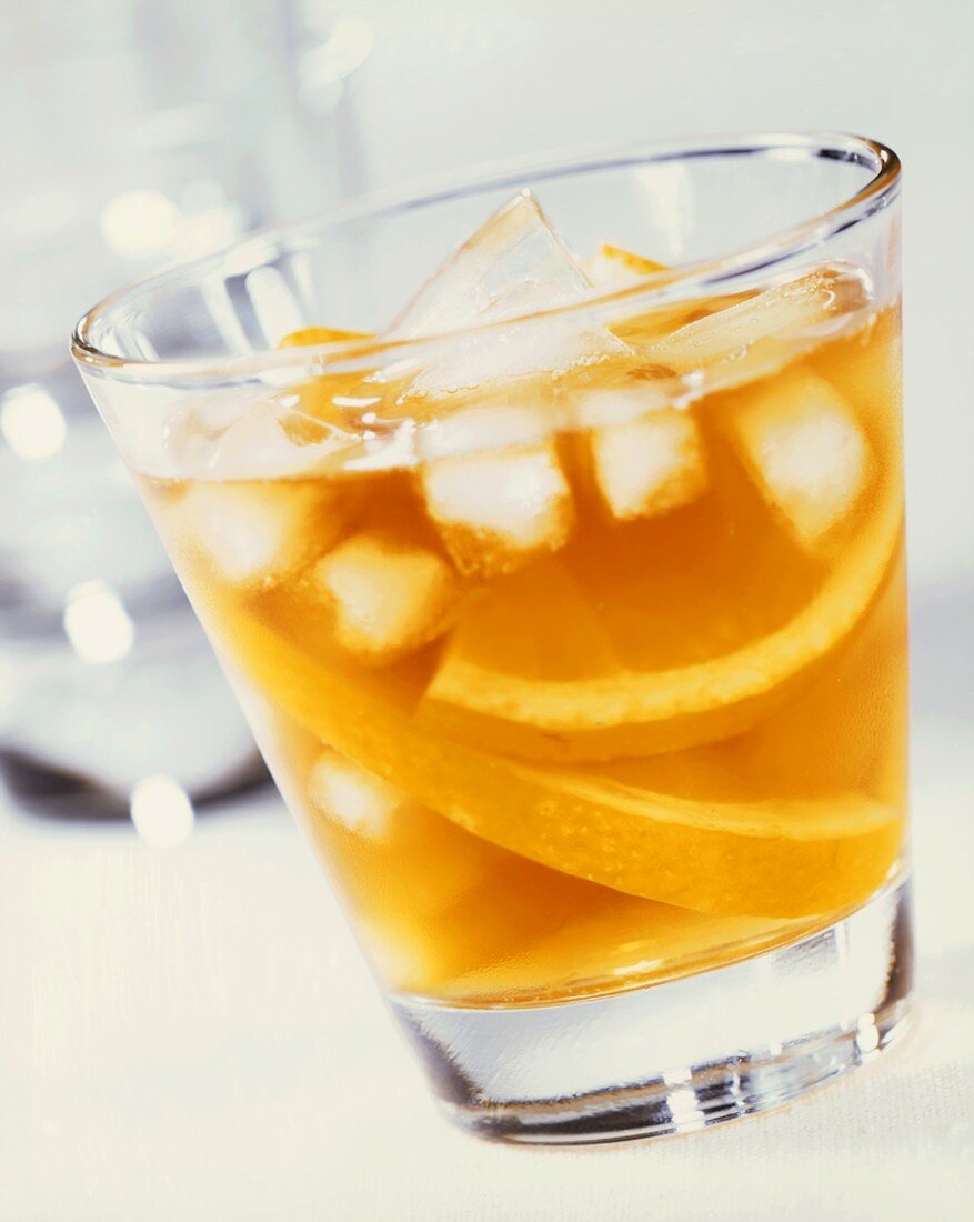 A glass of orange juice with ice cubes and orange slices