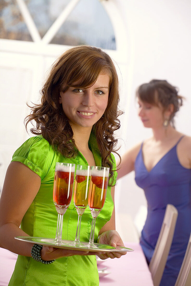 Young woman holding a tray of champagne and strawberries
