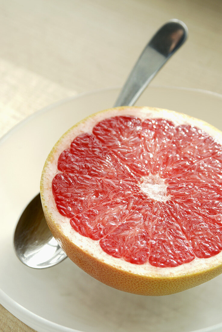 Halbe rosa Grapefruit mit Löffel