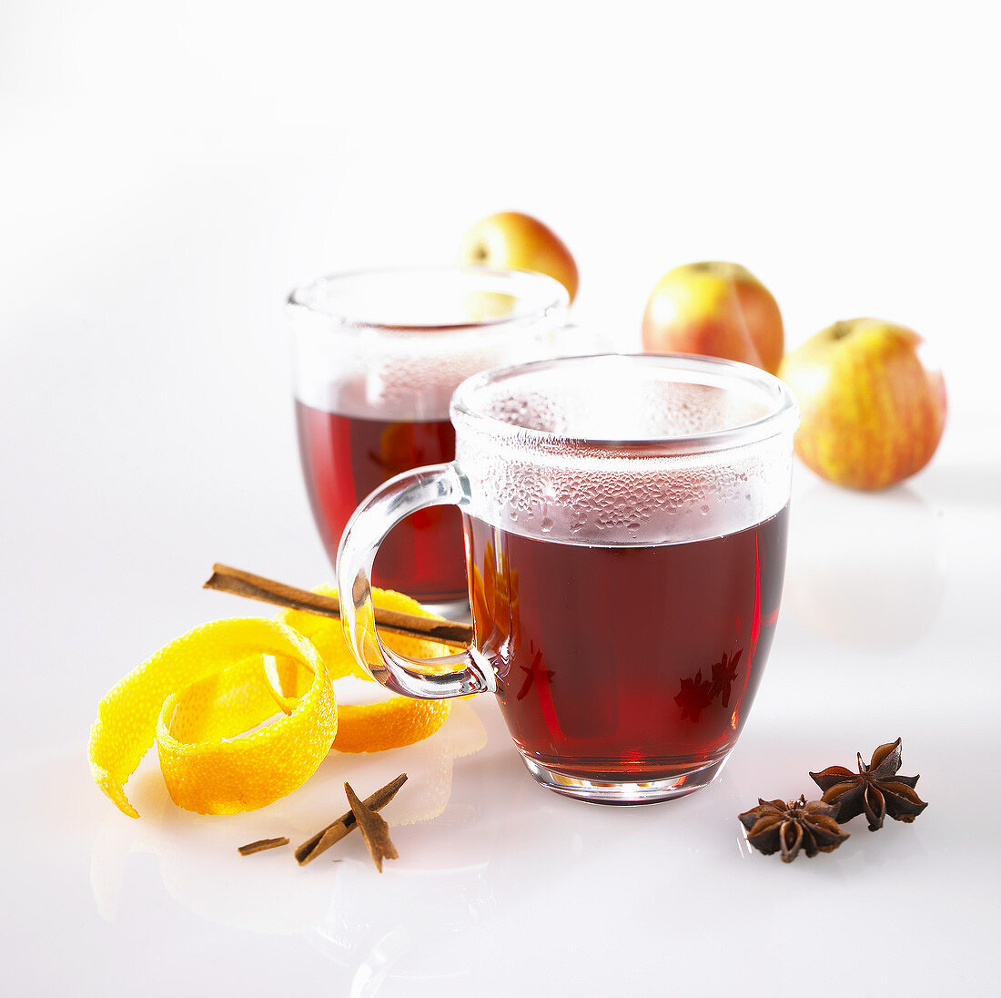 Mulled wine in glass mugs, orange peel, spices and apples