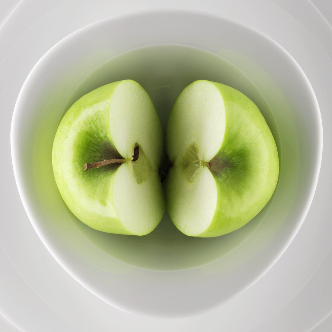 Halved green apple in a bowl