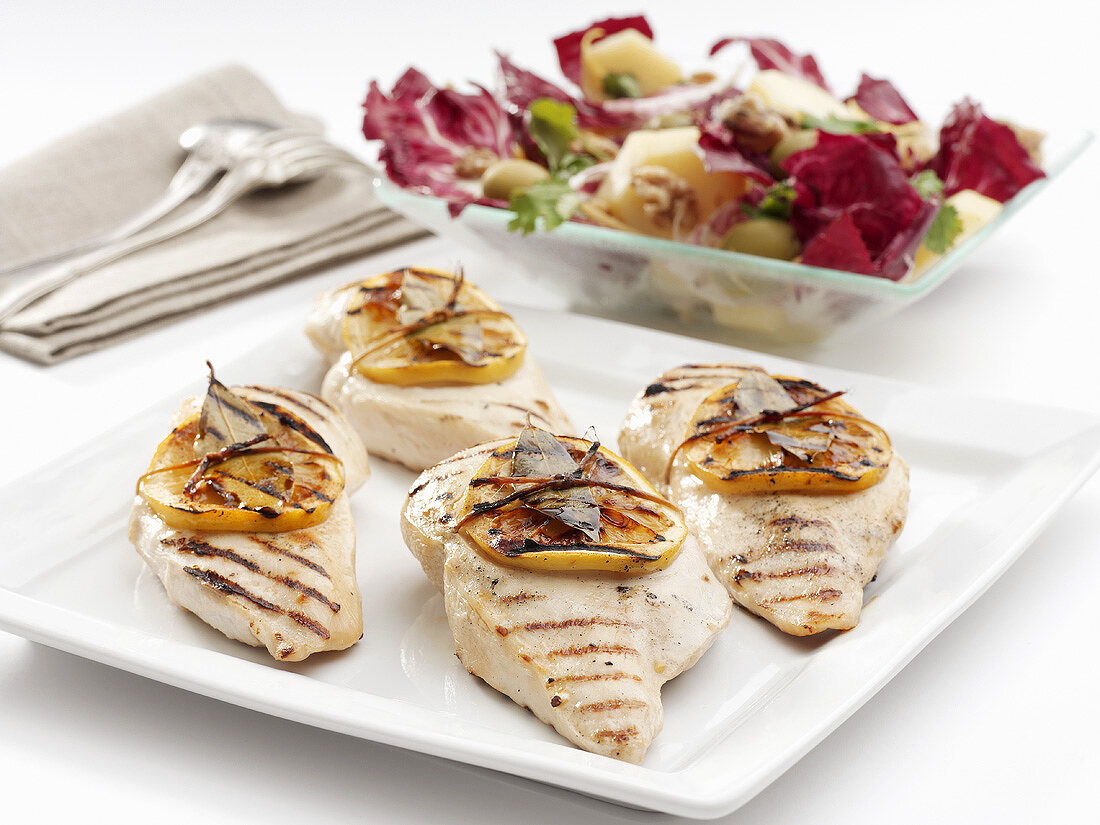 Grilled chicken breasts with slices of lemon and salad