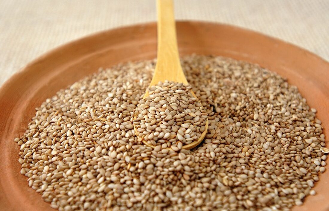 Sesame seeds in bowl and on wooden spoon