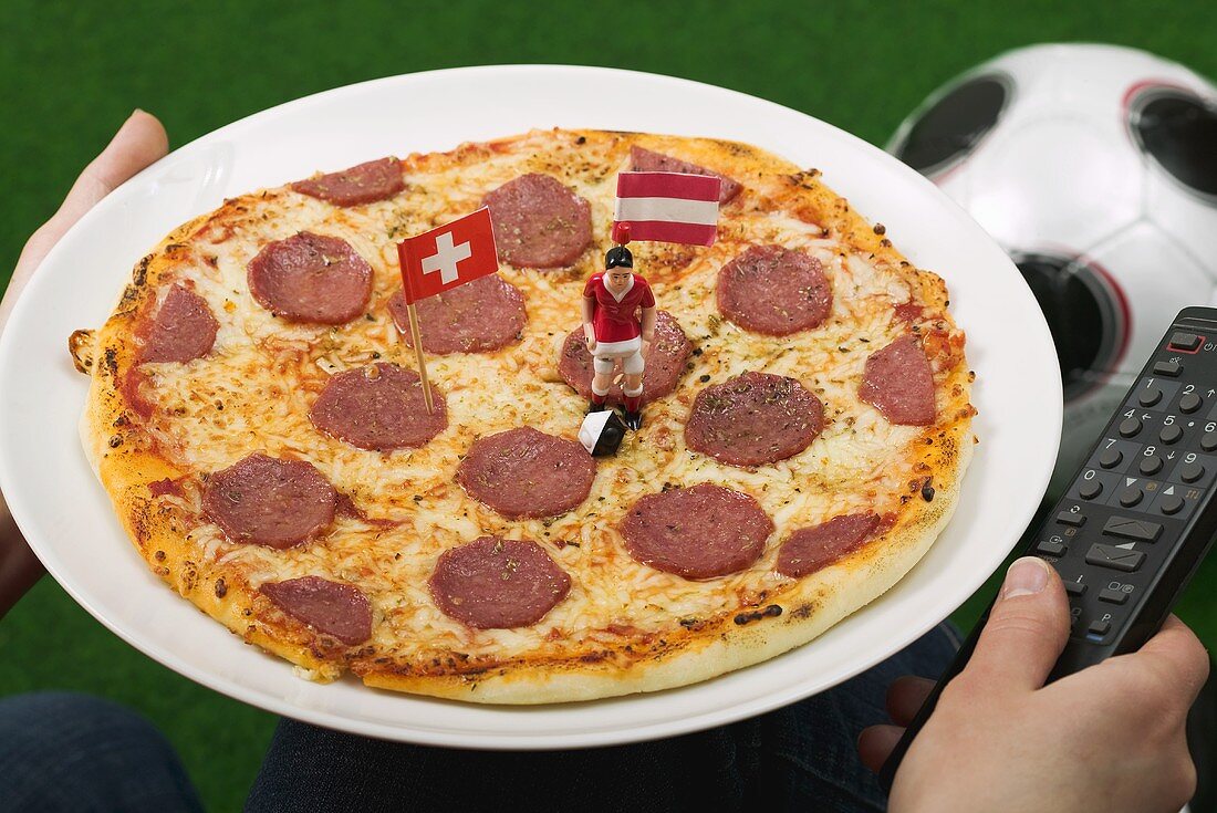 Salami pizza with flags and football figure