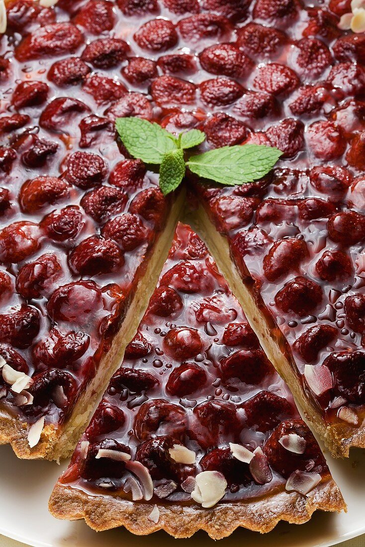 Strawberry tart with flaked almonds and mint leaves