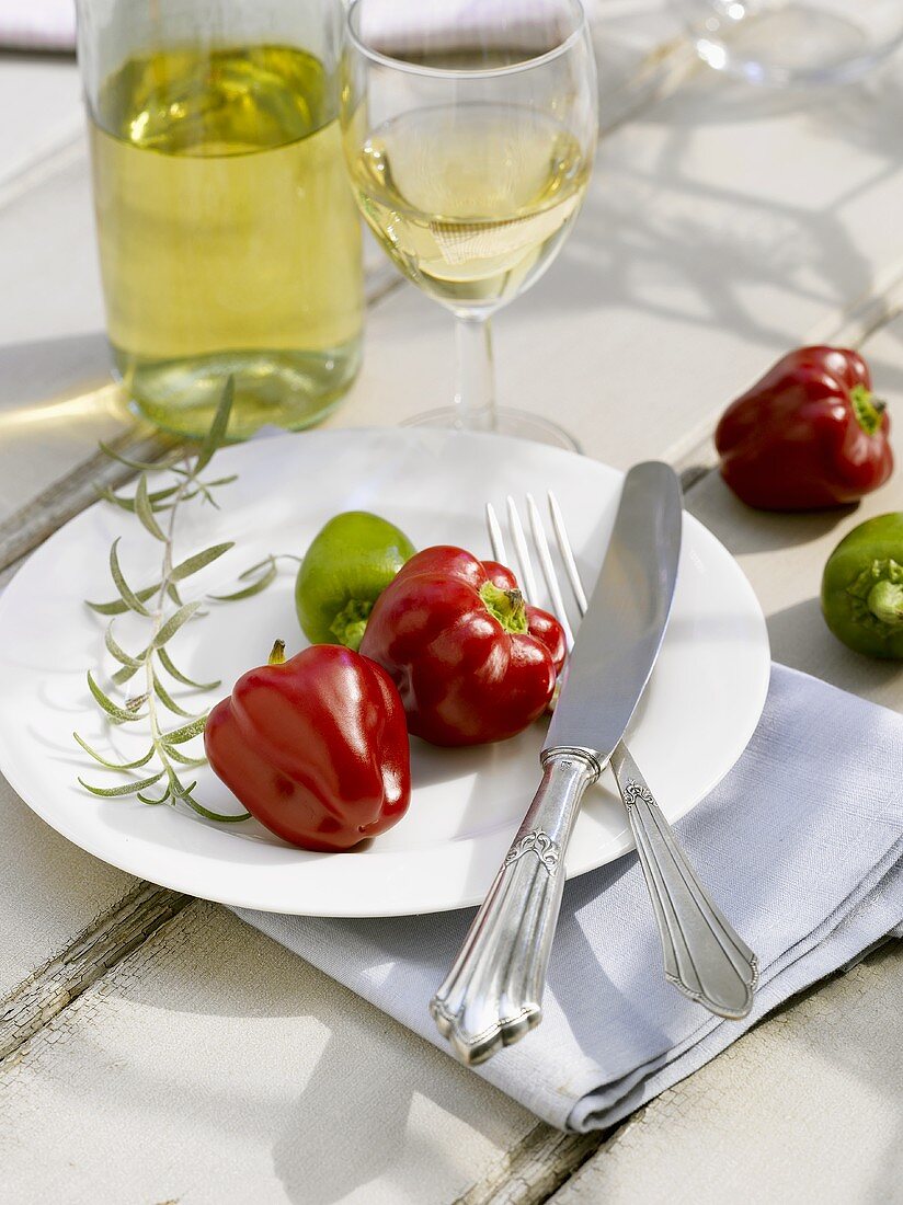Red and green chillies and silver cutlery on white plate