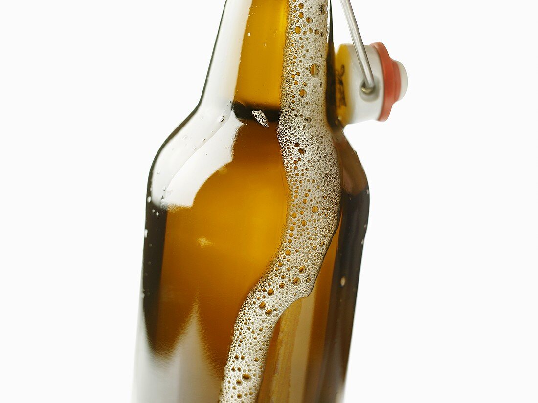 Bügelflasche mit herausschäumendem Bier