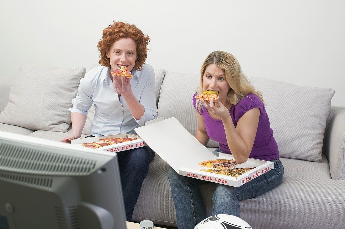 Zwei Freundinnen essen Pizza beim Fernsehen