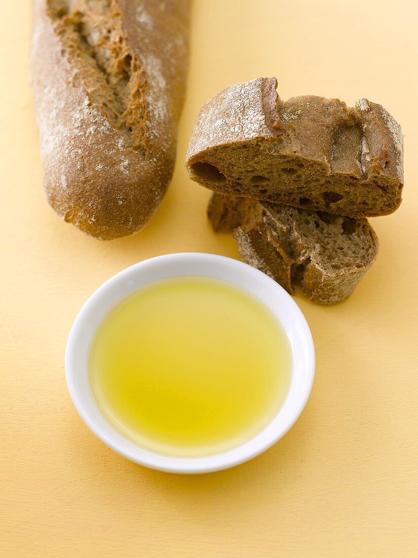 Roggenbaguette mit Olivenöl in weißem Porzellanschälchen