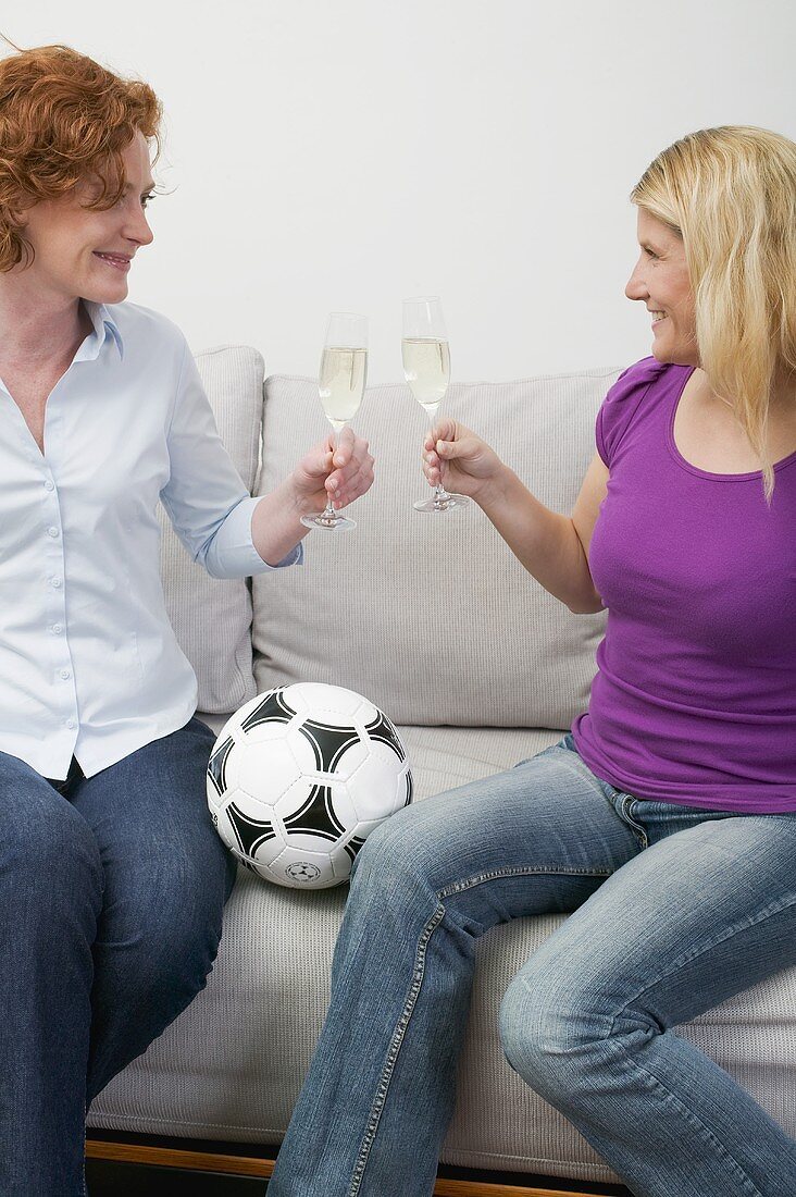 Two friends with sparkling wine and football