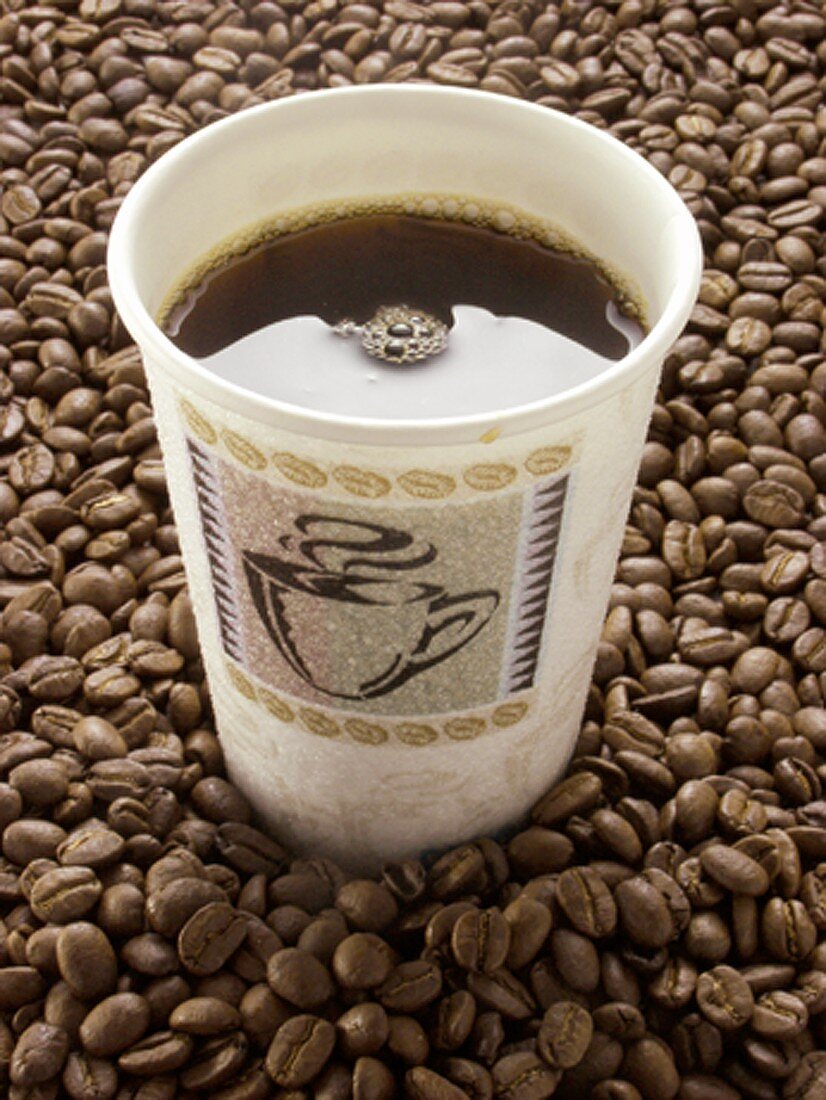 Schwarzer Kaffee im Pappbecher auf Kaffeebohnen