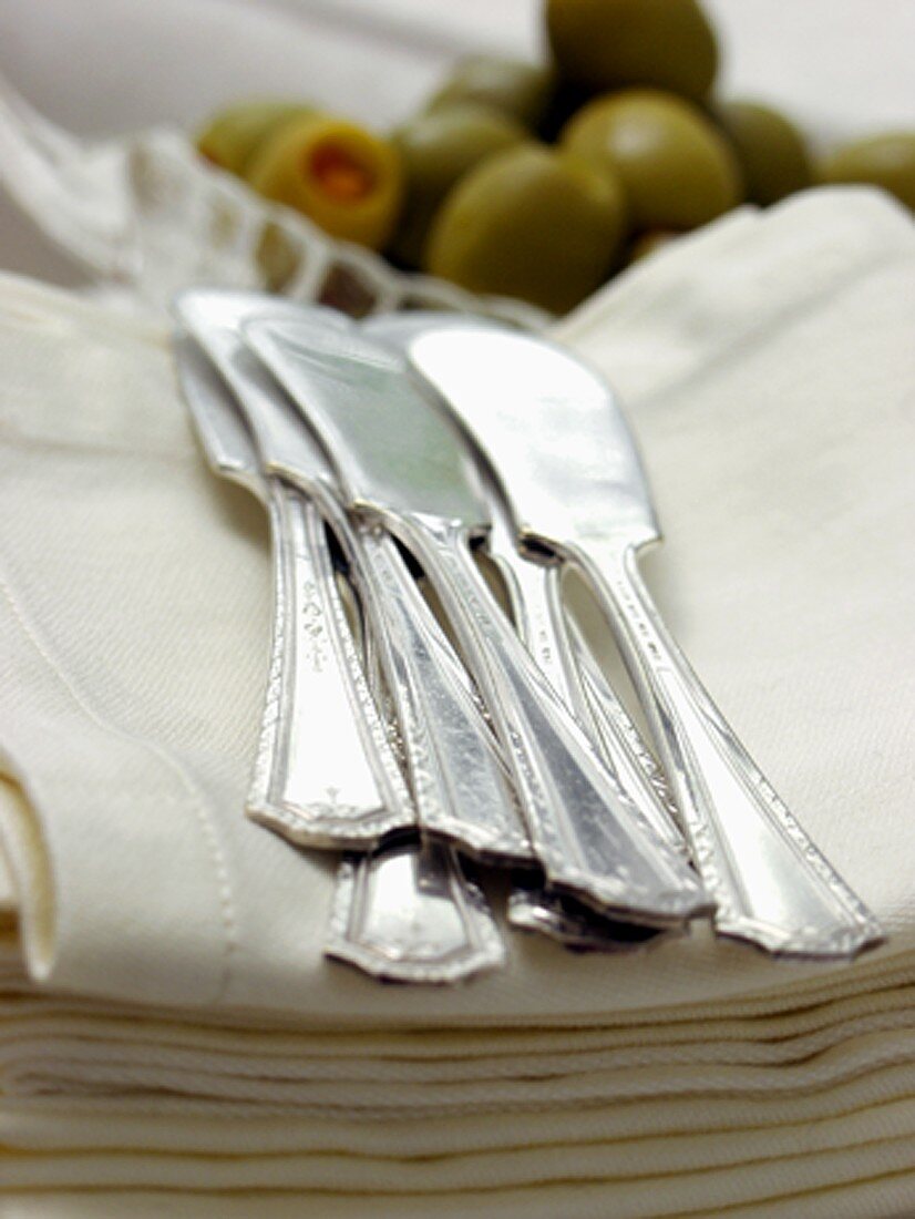 Butter Knifes Resting on Linen Napkins with Olives