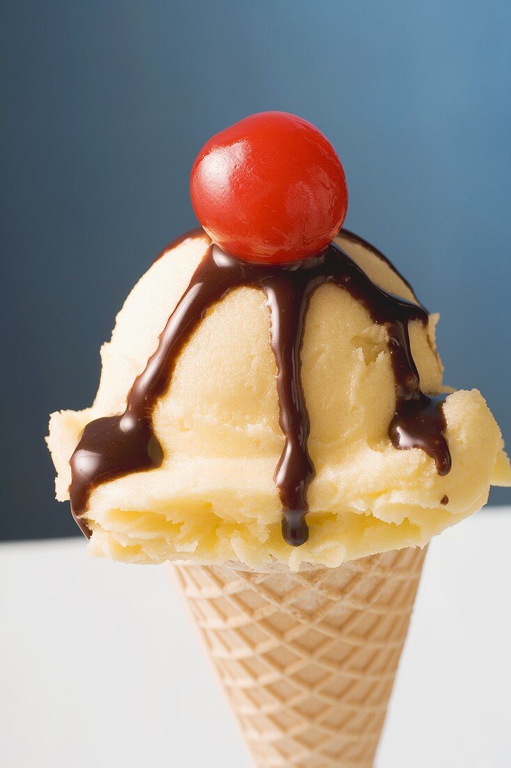 Ice cream with chocolate sauce and cocktail cherry in cone
