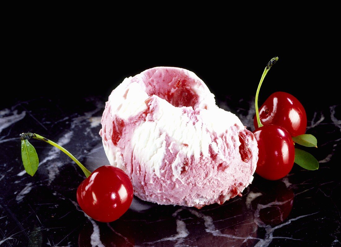 Cherry ice cream with cherries on marble slab