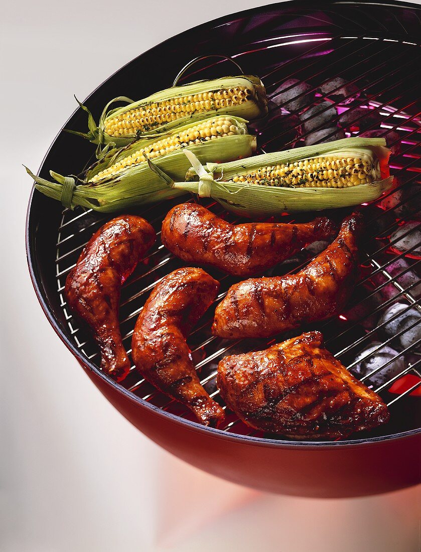 Hähnchenteile und Maiskolben auf dem Grill