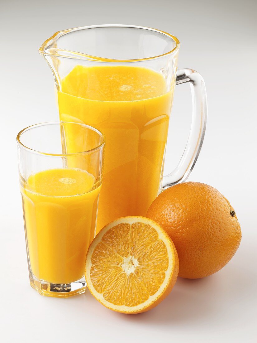 Orange juice in jug and glass, fresh oranges