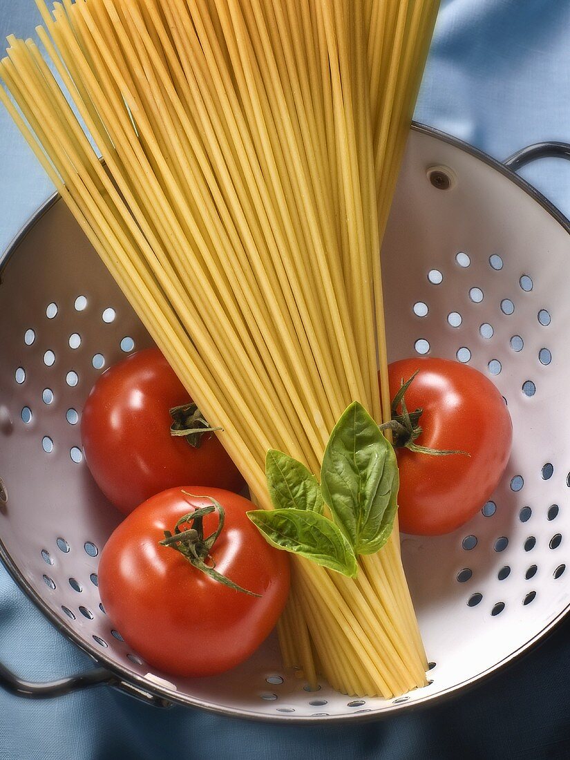 Spaghetti, Tomaten und Basilikum in einem Küchensieb