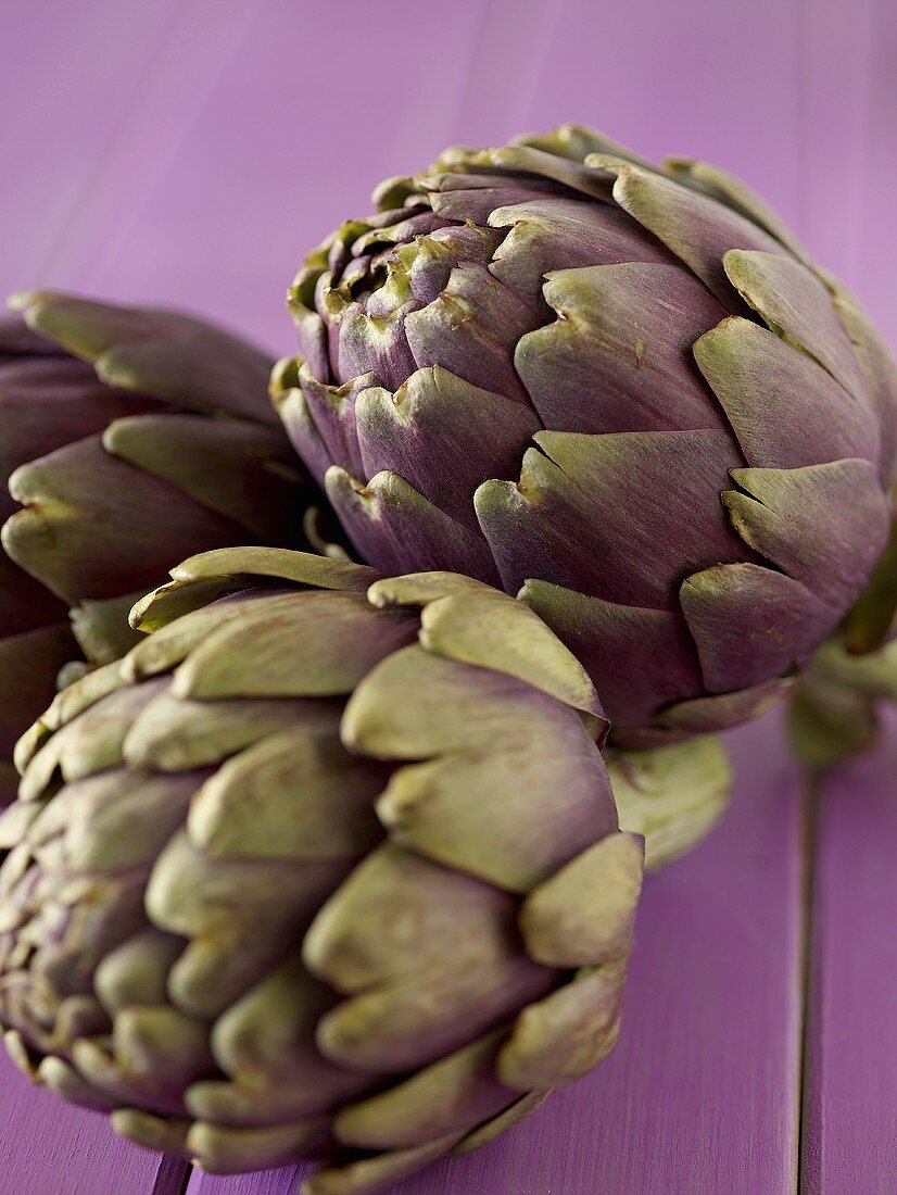 Three Purple Artichoke on Purple Wood