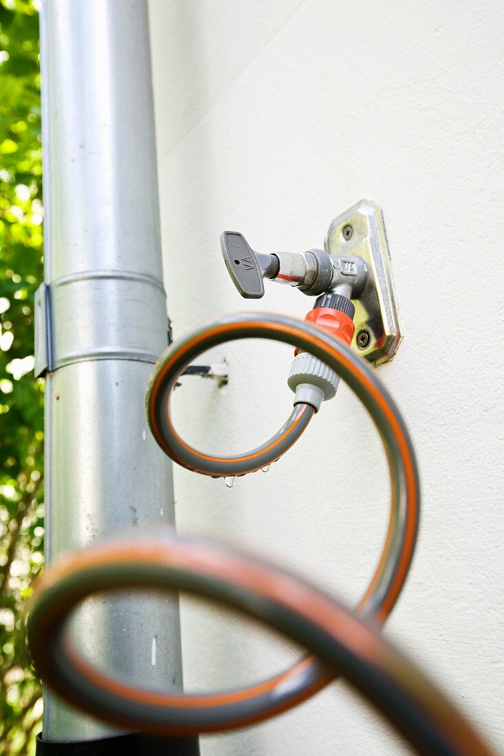 An outlet for a garden hose on a house wall