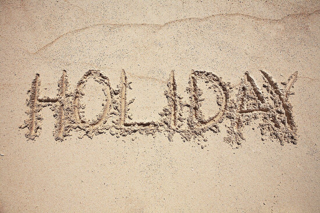 The word HOLIDAY written in sand