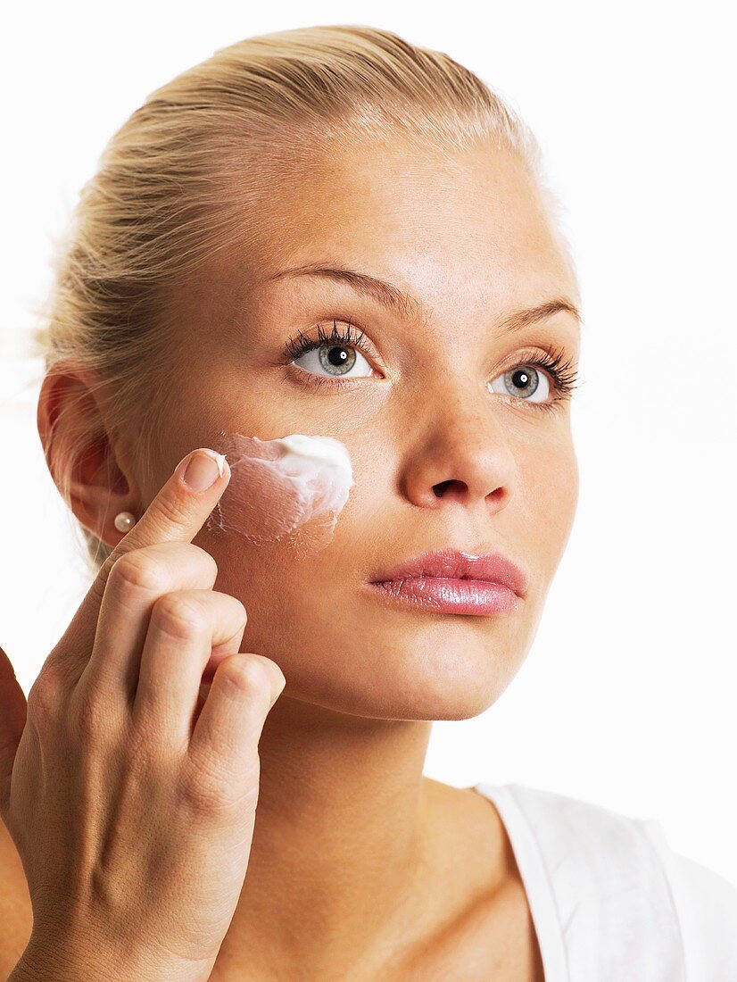 A woman applying face cream with her finger