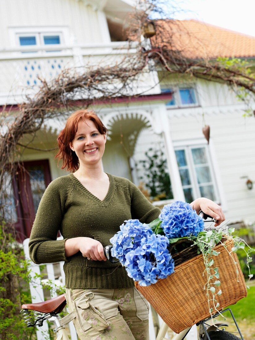 A woman with a bicycle in front of a house