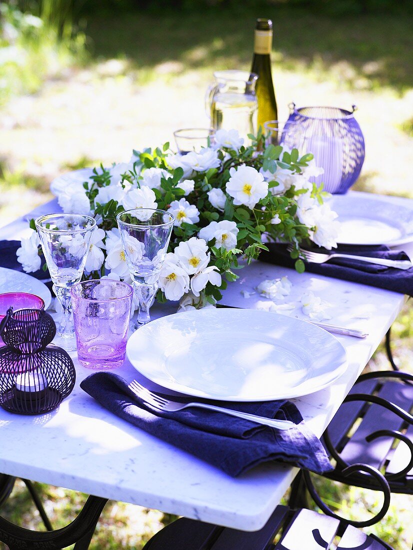 Gedecke und Blumendeko auf Gartentisch