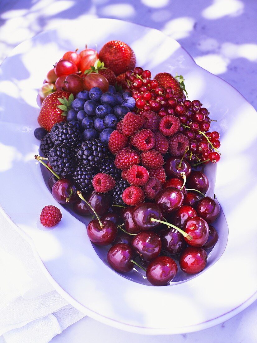 Frische Beeren und Kirschen auf weisser Platte