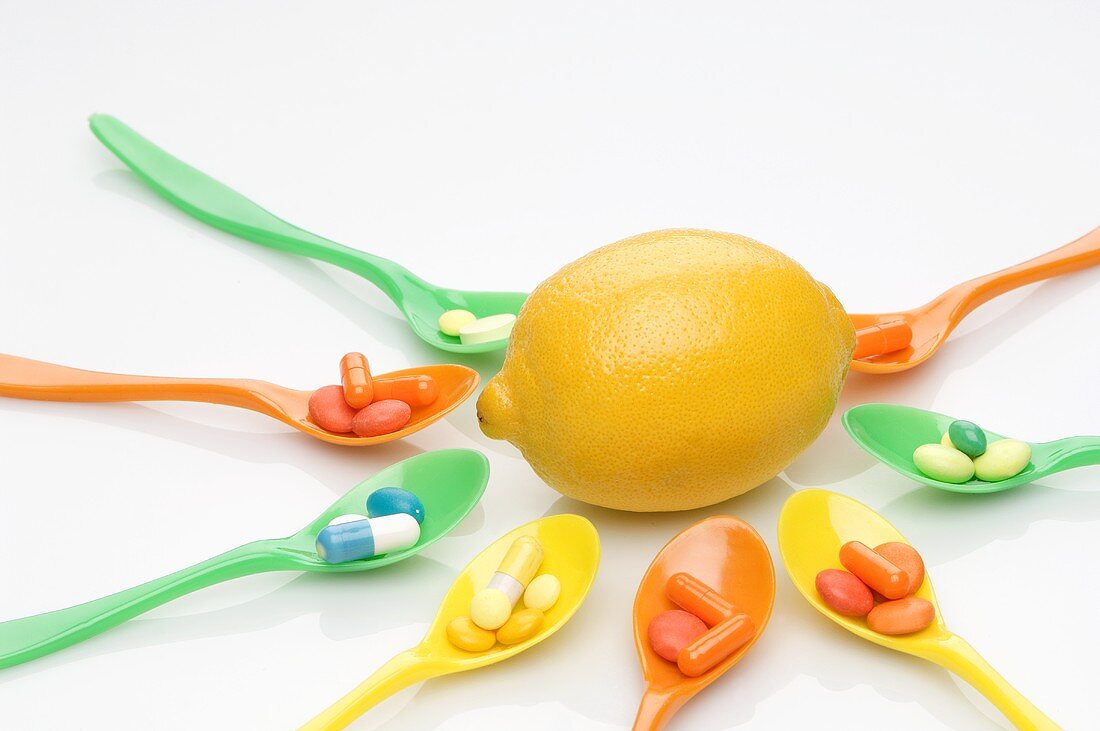 Spoons with vitamin tablets surrounding a lemon