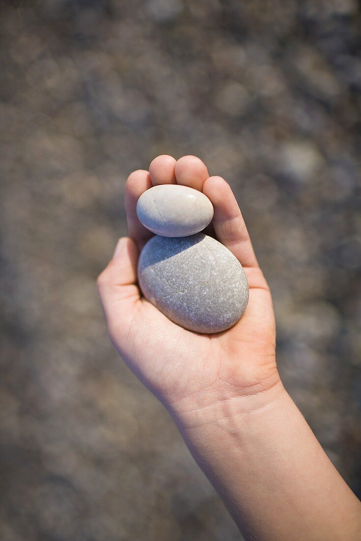 A hand holding pebbles
