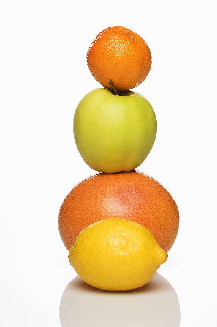 A stack of citrus fruits and an apple